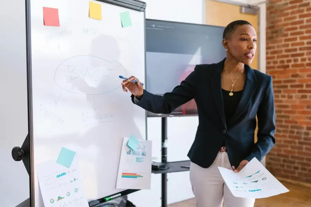 femme devant un tableau blanc expliquant sa stratégie marketing