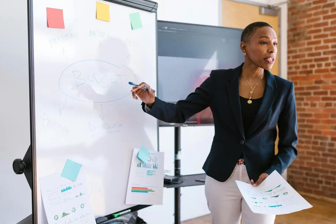 femme devant un tableau blanc expliquant sa stratégie marketing